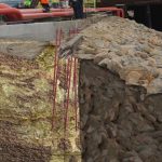 Cross-section of a volcanic rock showing layers with rusty iron rods.